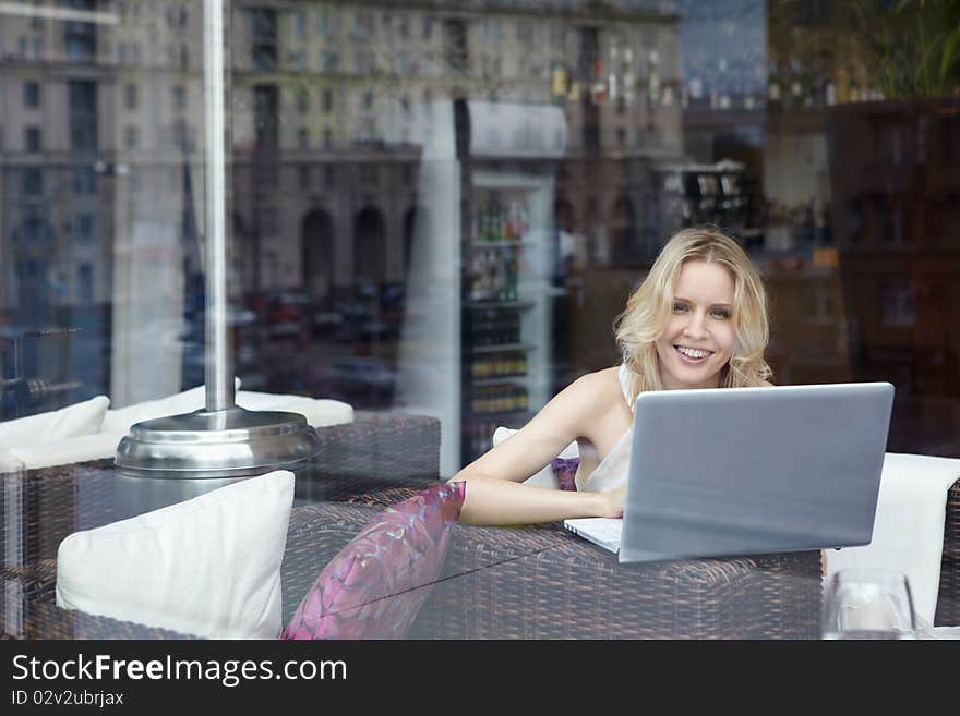 Happy young girl with laptop in restaurant. Happy young girl with laptop in restaurant