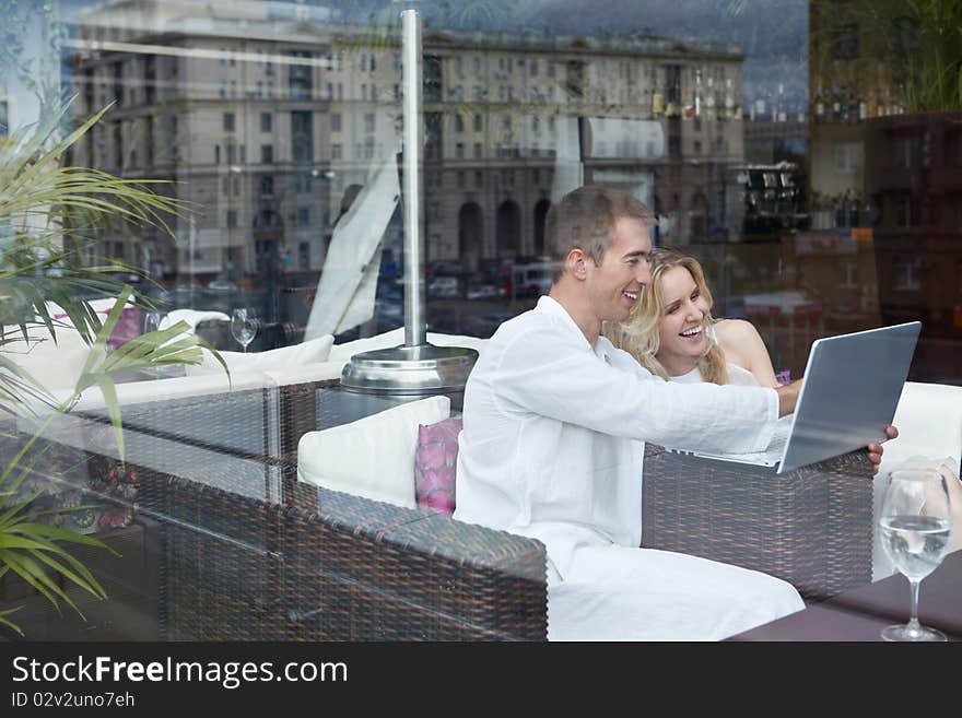 Laughing young couple looking at laptop in a restaurant. Laughing young couple looking at laptop in a restaurant