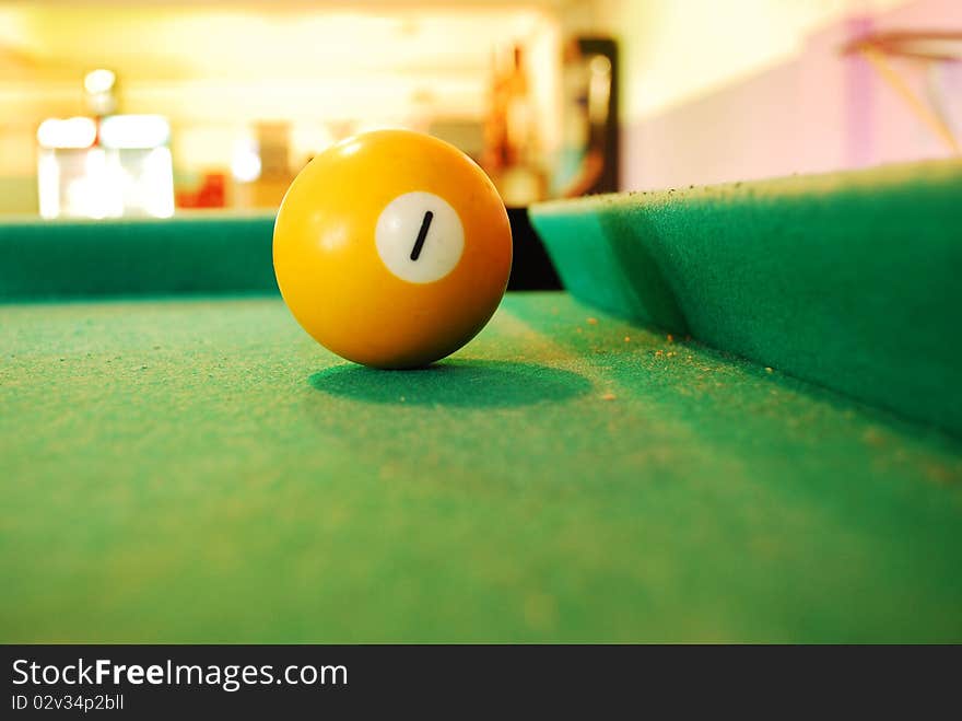 Closeup of a yellow Billiard Ball on green layout table