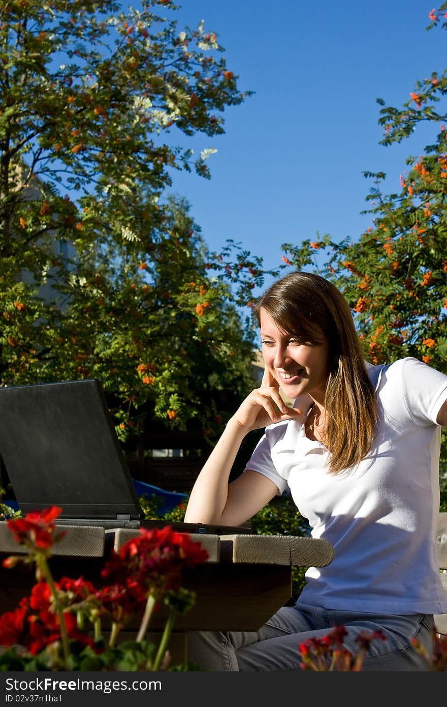 Young pretty woman with laptop sitting on the bench in a park. Young pretty woman with laptop sitting on the bench in a park