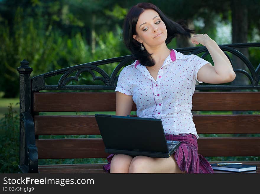 Young beautiful student girl with laptop in the park. Young beautiful student girl with laptop in the park