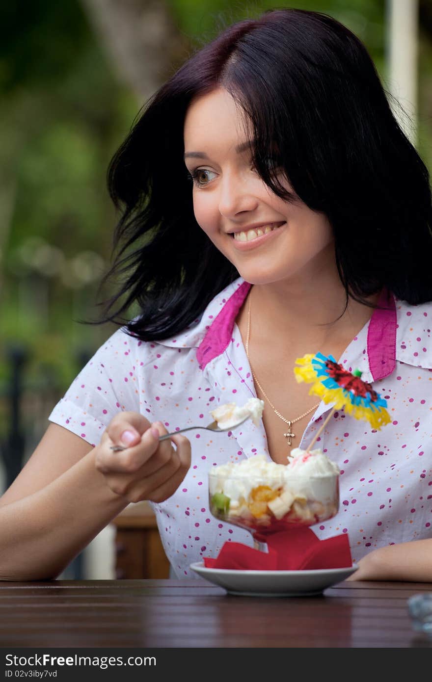 Young beautiful woman eating an ice cream in cafe. Young beautiful woman eating an ice cream in cafe