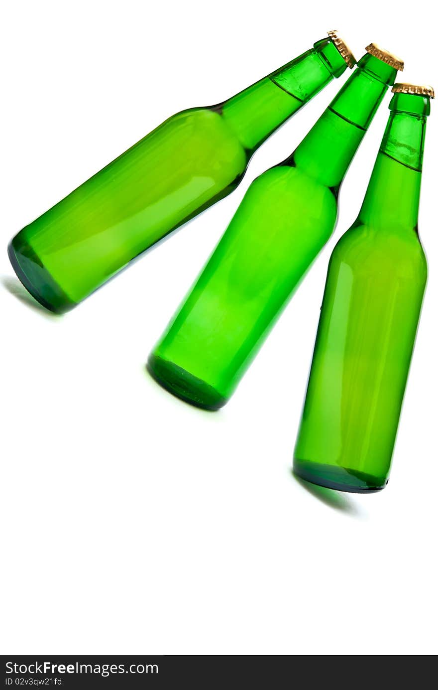 Three cold beers in green bottles isolated on white. Soft shadow. Three cold beers in green bottles isolated on white. Soft shadow