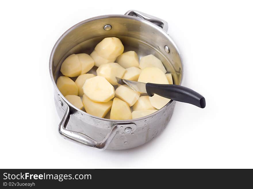 A pot with freshly peeled potatoes which still stuck the knife. The whole composition on white background. A pot with freshly peeled potatoes which still stuck the knife. The whole composition on white background.