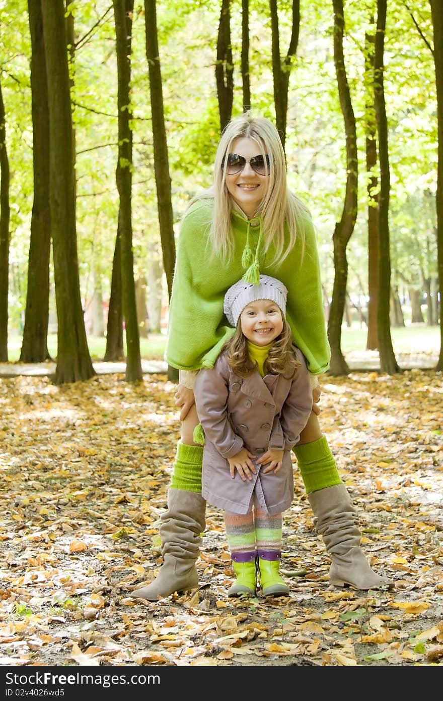 The woman with the child stand nearby and hands hold in a lap. The woman with the child stand nearby and hands hold in a lap