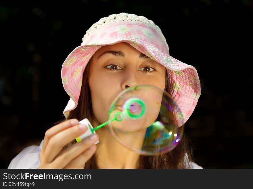 Portrait of a funny young girl in the bonnet blowing bubbles at summertime. Portrait of a funny young girl in the bonnet blowing bubbles at summertime