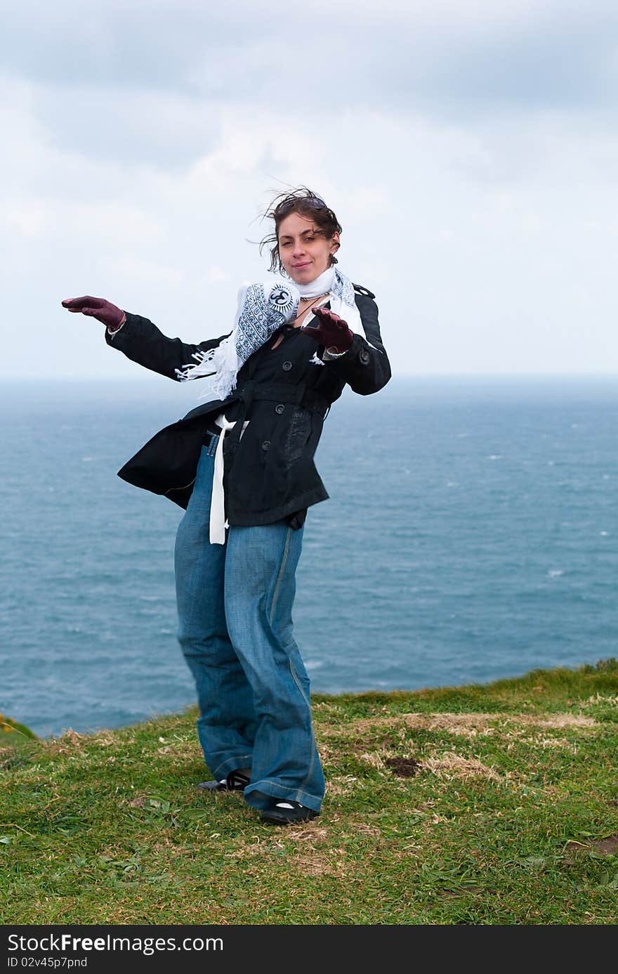 A girl on a top of cliff in front of the ocean in windy cloudy day. A girl on a top of cliff in front of the ocean in windy cloudy day