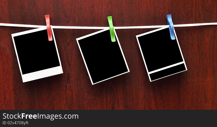 Frames attached to a rope on clothespins against a wooden background