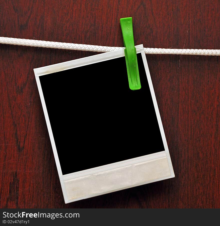 Frames attached to a rope on clothespins against a wooden background