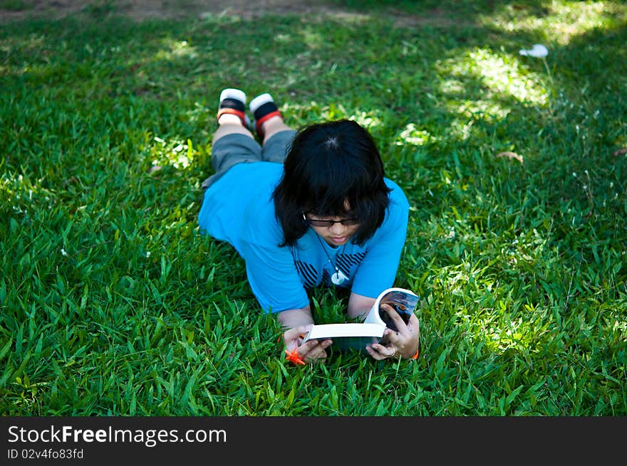 Little girl reading a book in the park.