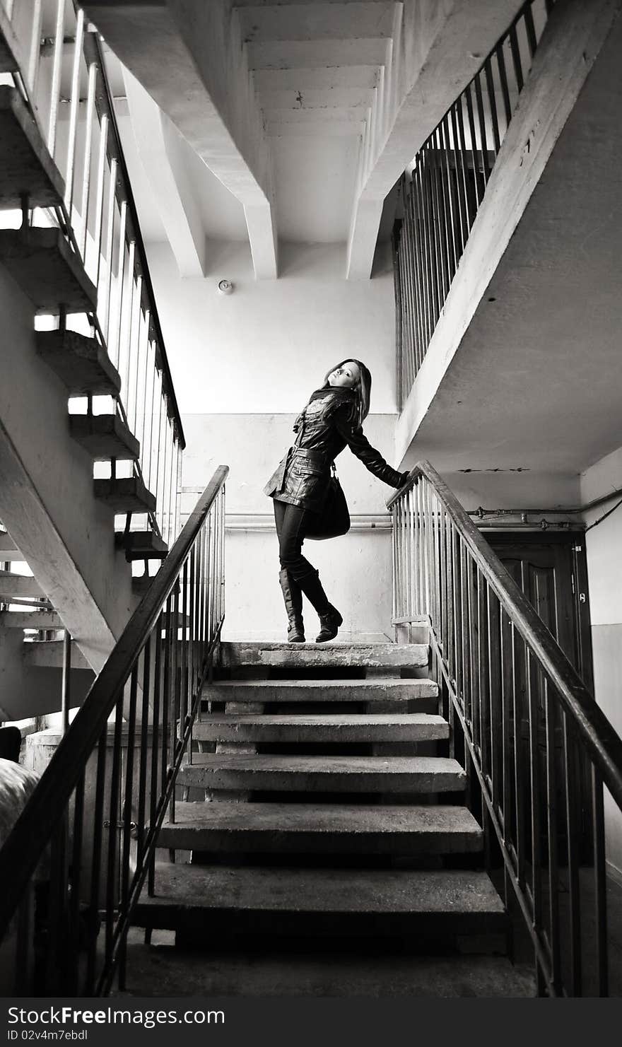 The beautiful girl is standing on stairs and posing looking at the camera. The beautiful girl is standing on stairs and posing looking at the camera