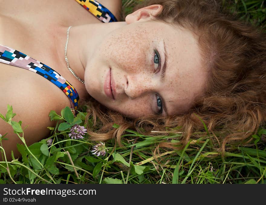 Beautiful ginger girl is lying in the green grass