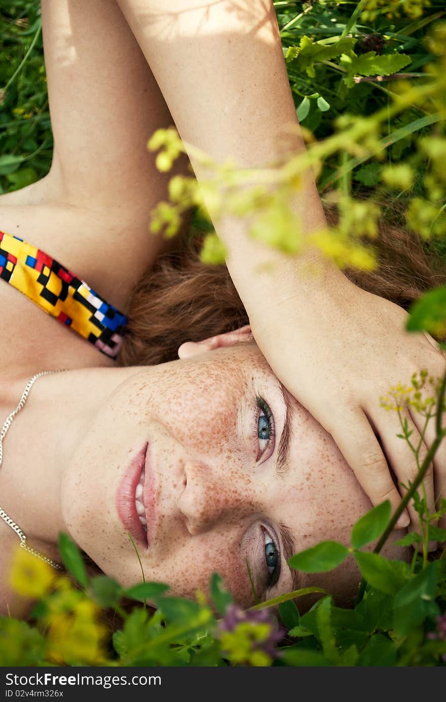 Beautiful ginger girl is lying in the green grass