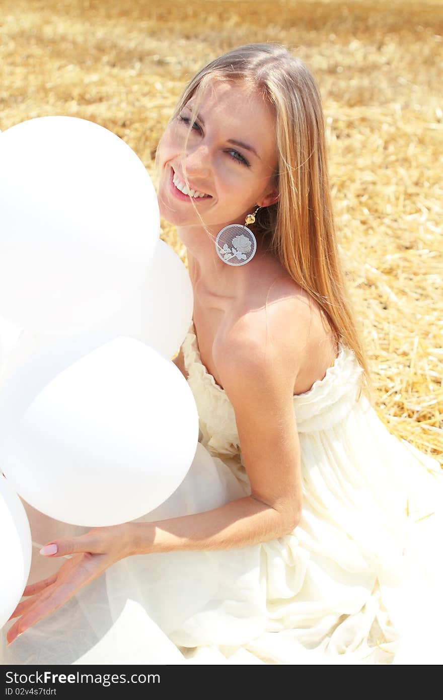 Blond smiling girl with white balloons in the field. Blond smiling girl with white balloons in the field