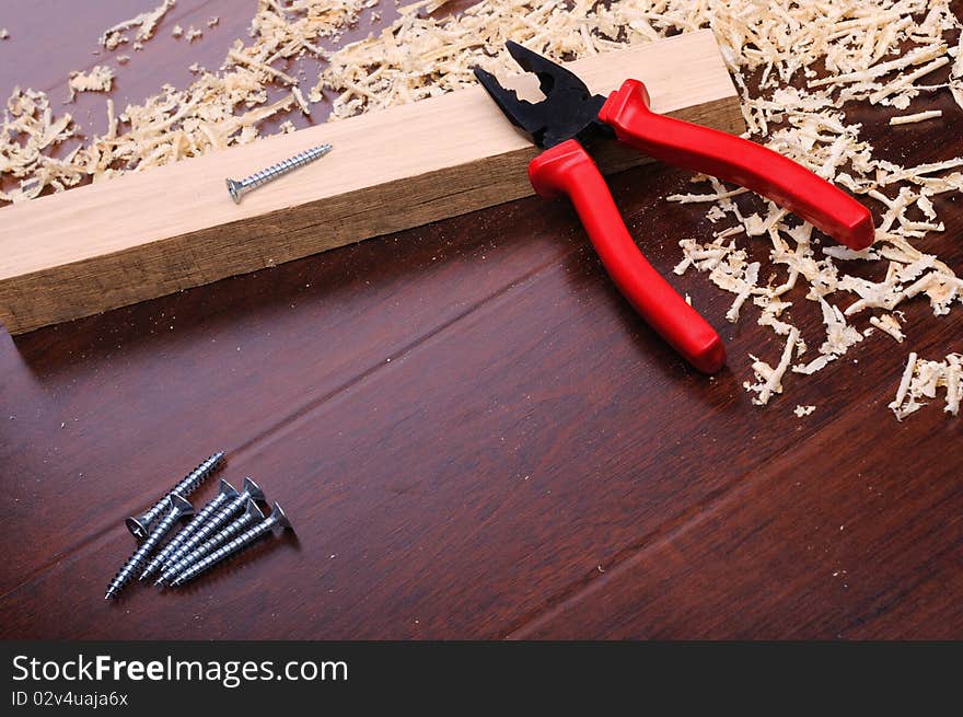 Shavings of wood, brick red and pliers on a dark background