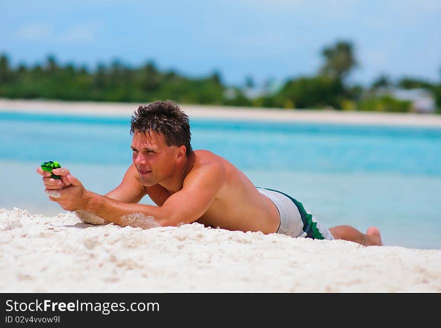 Man playing with toy water guns on exotic beach. Man playing with toy water guns on exotic beach