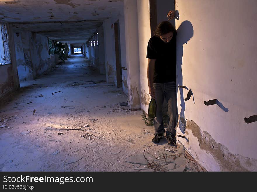 Staggering Alcoholic in a Corridor, Holding a Bottle