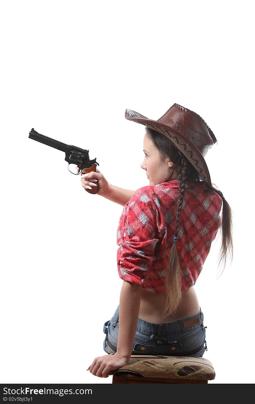 Pretty young girl in the cowboy hat with two pigtails with revolver aim. Pretty young girl in the cowboy hat with two pigtails with revolver aim