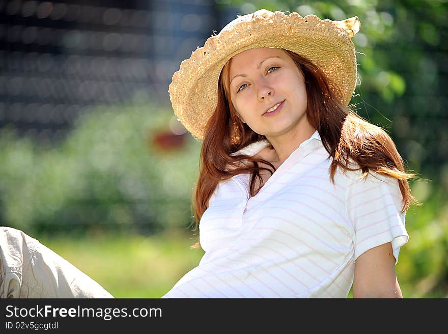 Young woman in straw hat  sitting on green grass