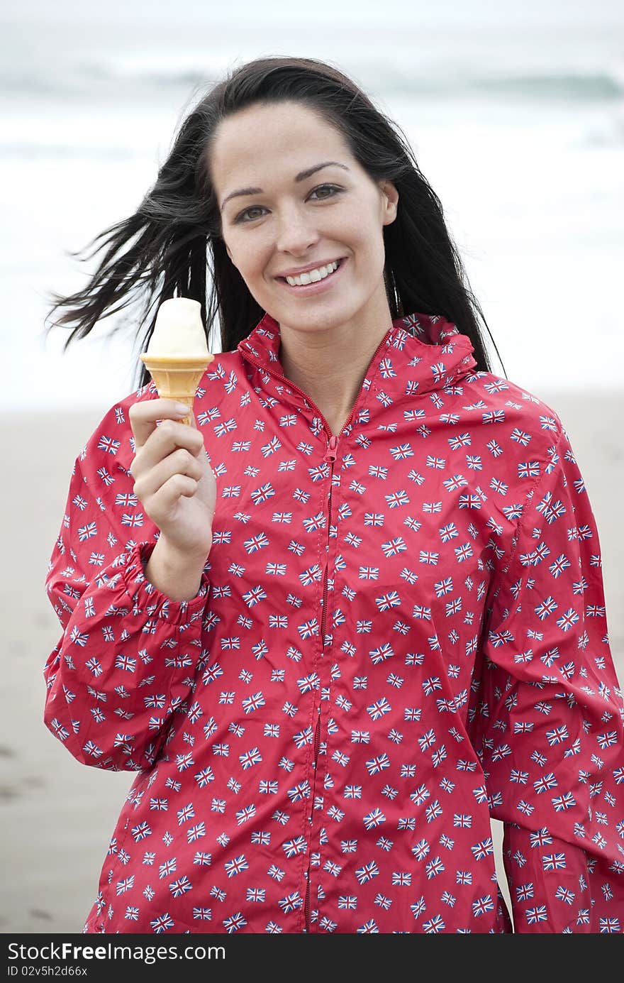 Woman wearing raincoat holding an ice cream at the beach