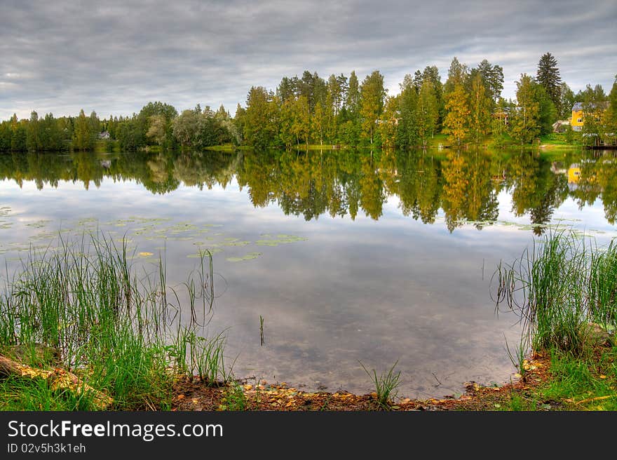 HDR photo of finnish scenery, with lake and forest and foreground of shore