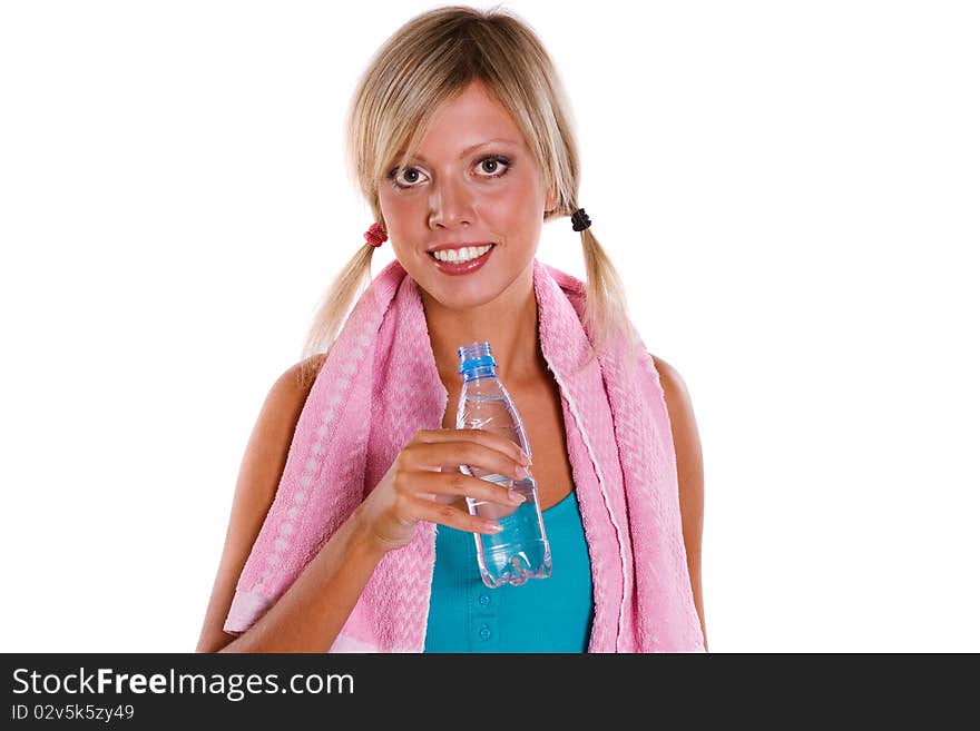 A girl holding water with a towel over her shoulder after a workout. Young woman drinking water and relaxing after a healthy workout. A girl holding water with a towel over her shoulder after a workout. Young woman drinking water and relaxing after a healthy workout.