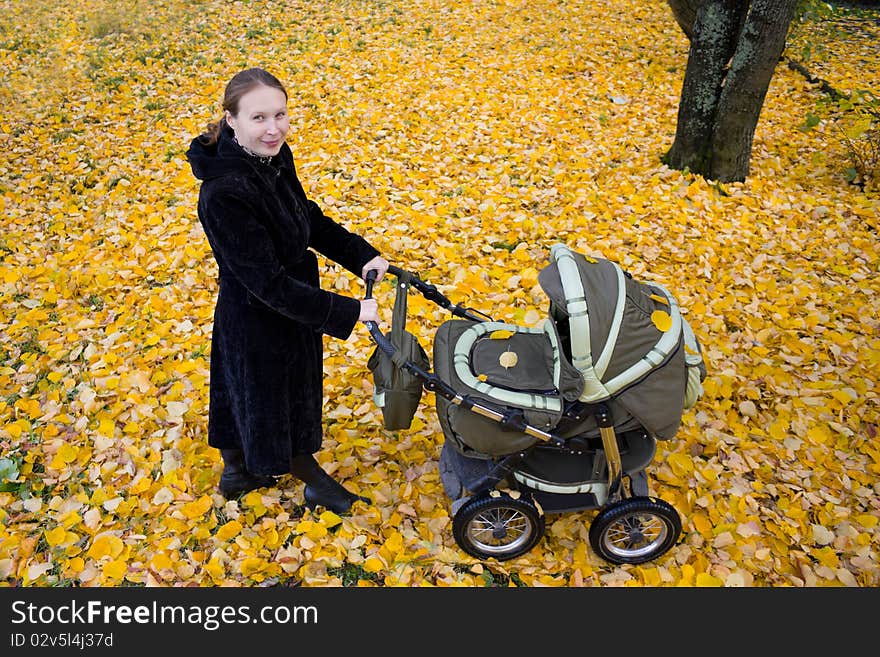 Mother with a stroller in autumn park. Mother with a stroller in autumn park.