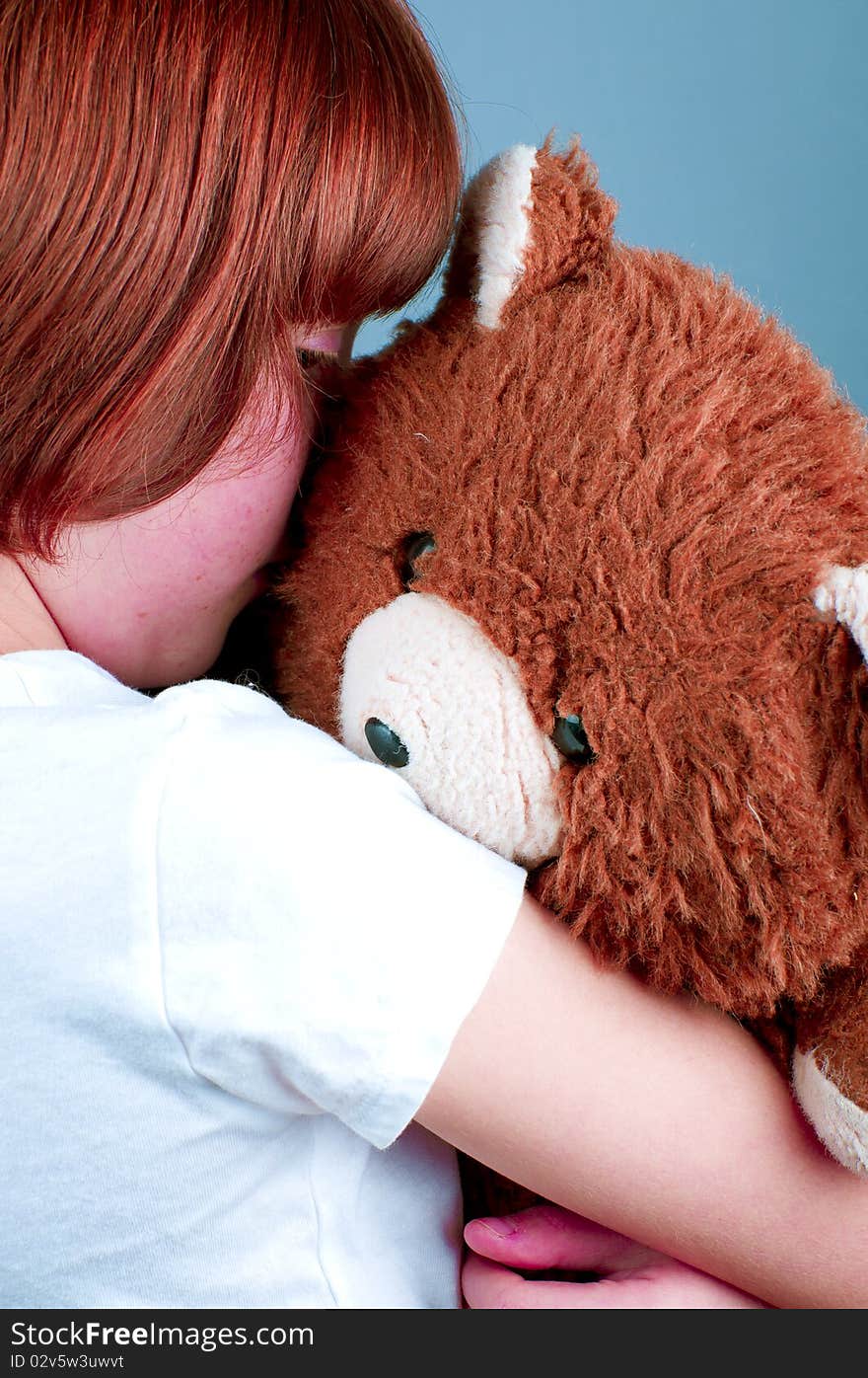 Beautiful redhead girl hugs a teddy bear.