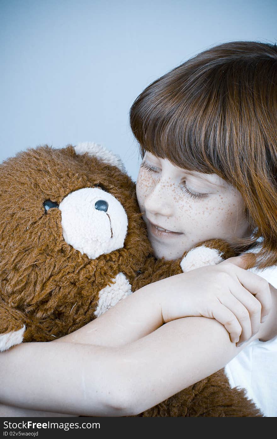 Beautiful redhead girl hugs a teddy bear.