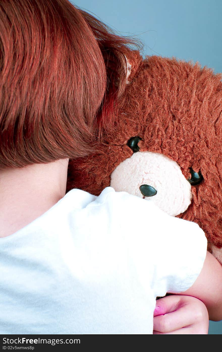 Beautiful redhead girl hugs a teddy bear.