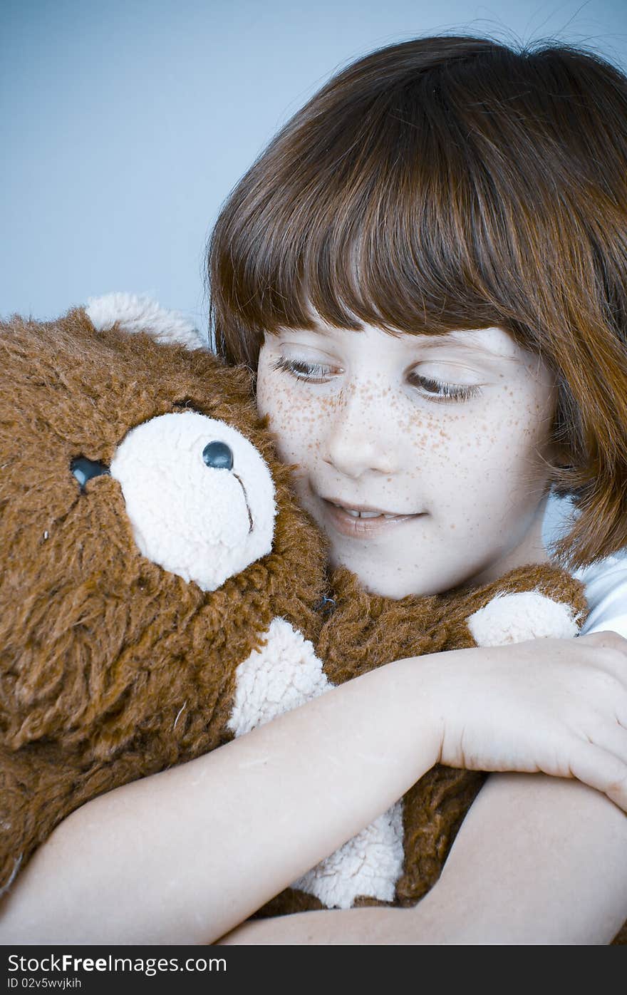 Beautiful redhead girl hugs a teddy bear.