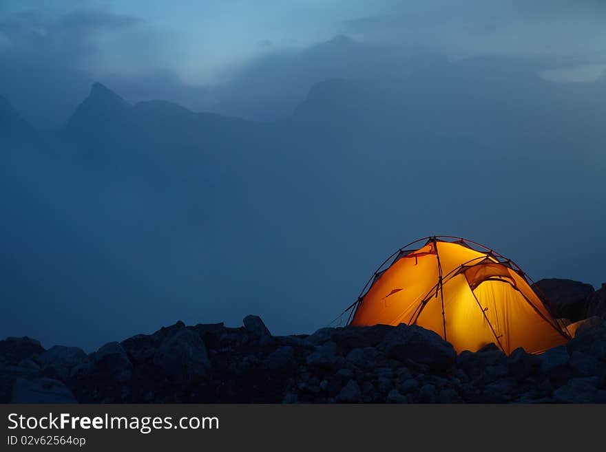 Evening in the Caucasus mountains and orange tent on a stones
