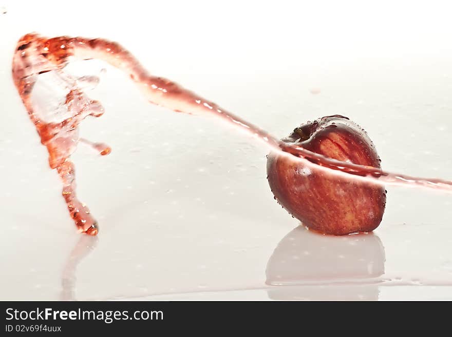 A golden red apple with a splash of water