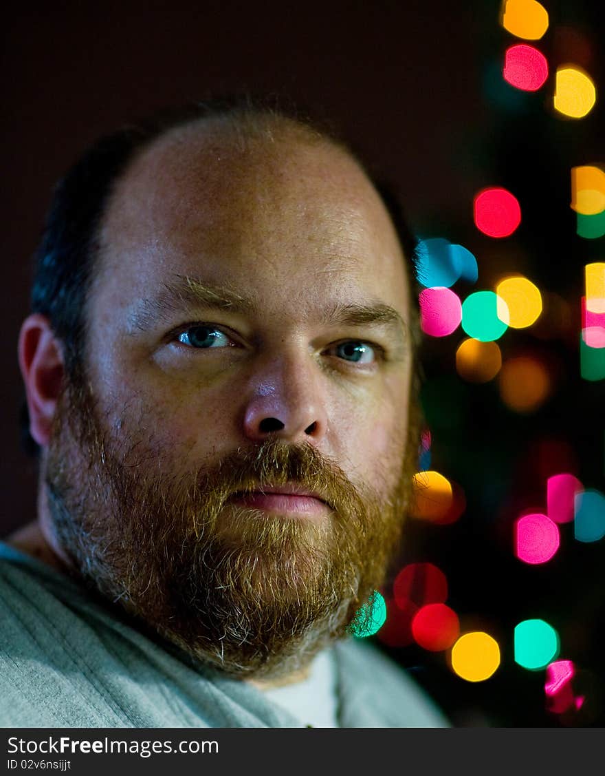 A mand looking sad in front of christmas tree. A mand looking sad in front of christmas tree