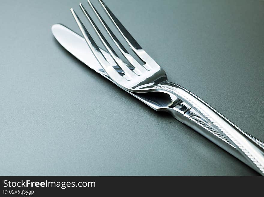 Silver fork, knife and spoon  over grey background. Silver fork, knife and spoon  over grey background.