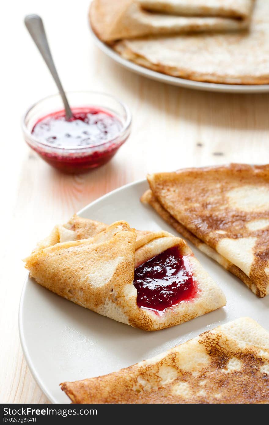 Pancakes with cranberry jam. Stack of pancakes and jam in background. Pancakes with cranberry jam. Stack of pancakes and jam in background