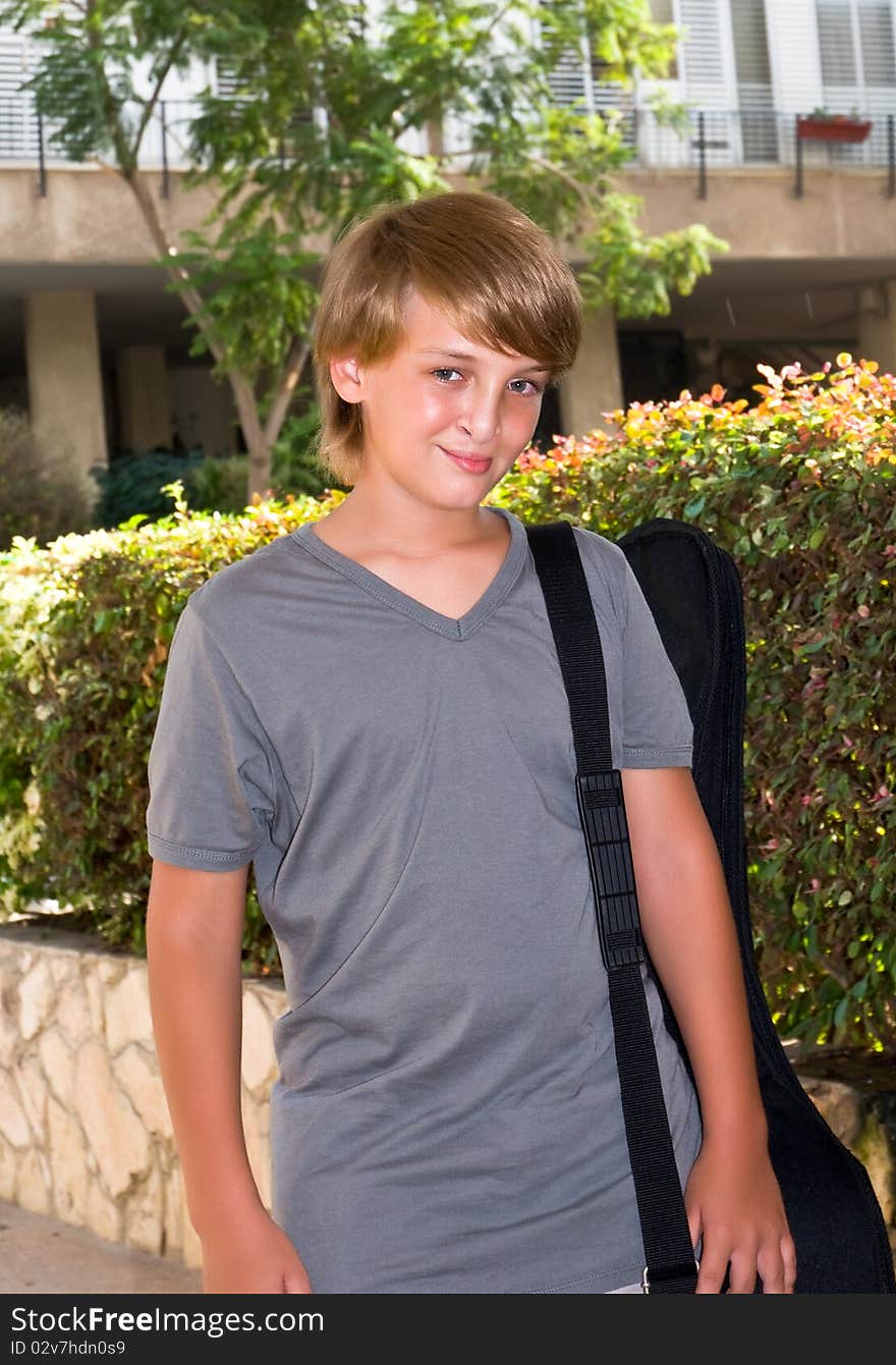 Portrait of a boy with a guitar in its case.