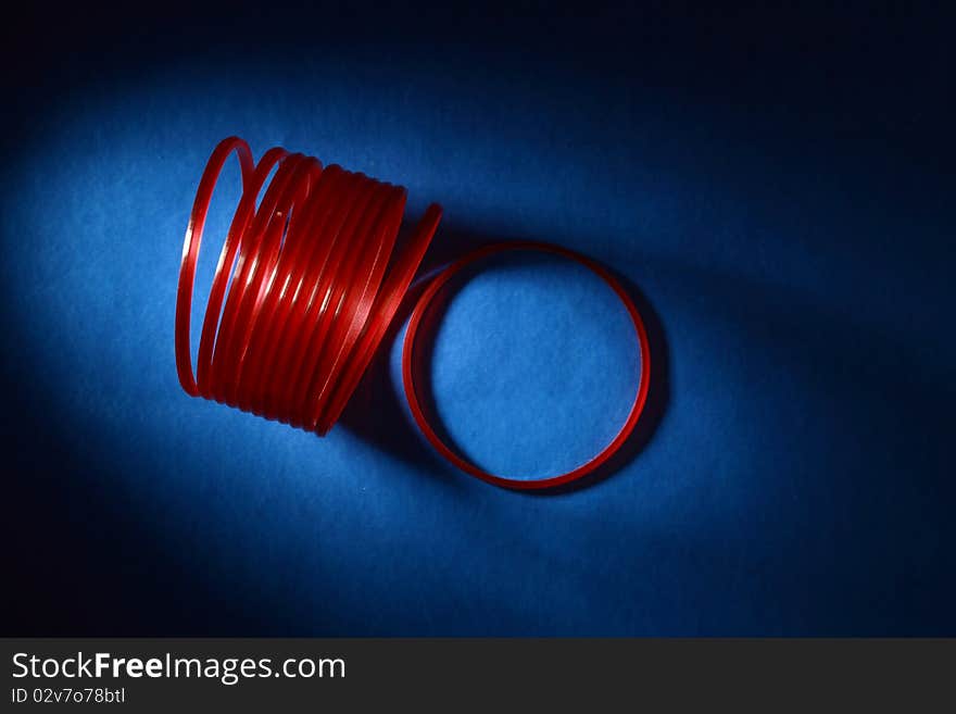 Abstract image of red bangles in dark blue background. Abstract image of red bangles in dark blue background