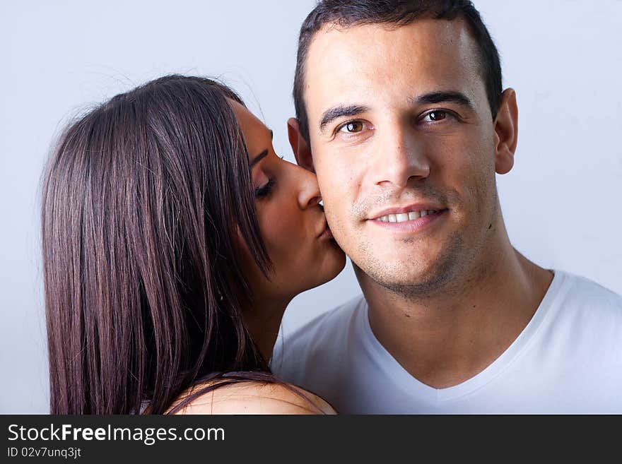 Woman leaning over kissing man on cheek. Woman leaning over kissing man on cheek