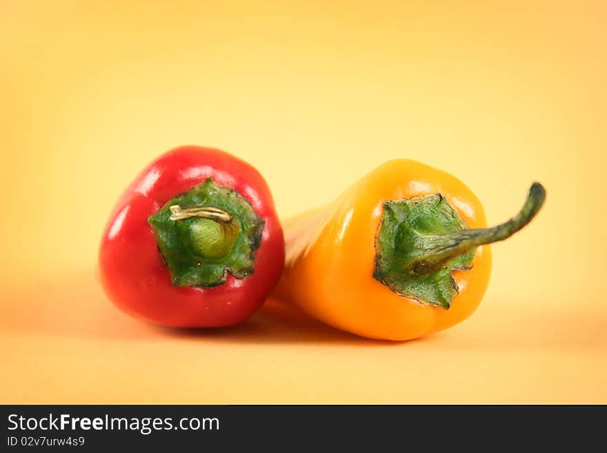 Hot red and yellow chili peppers on yellow background