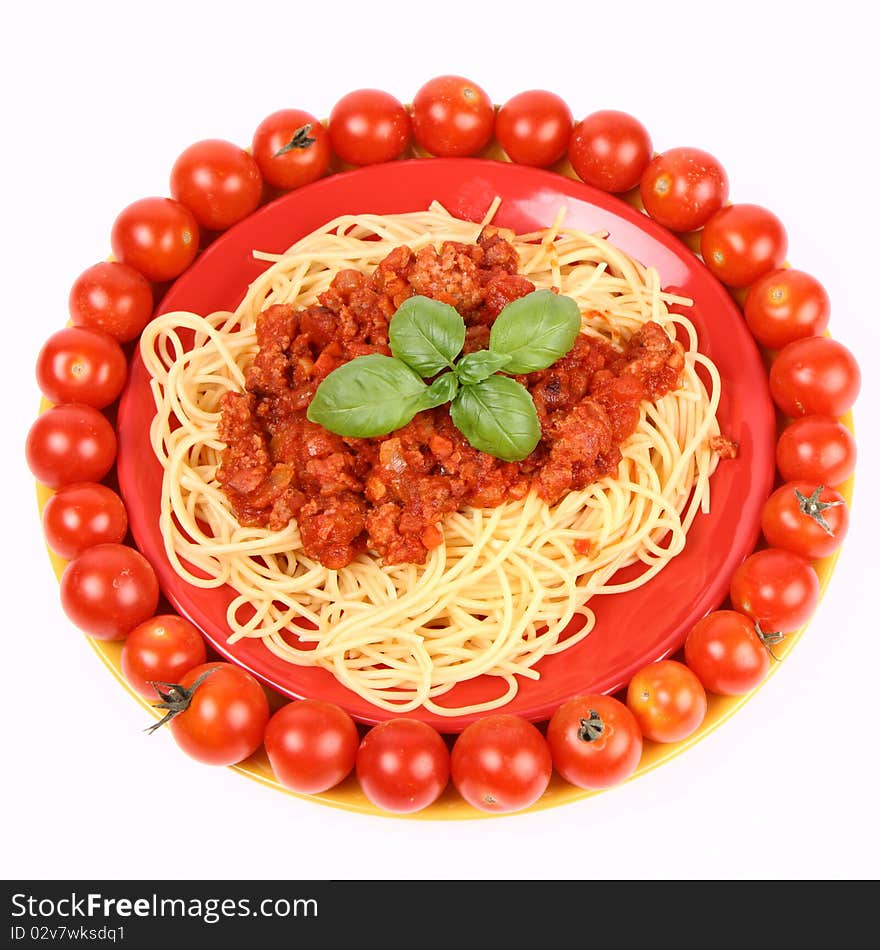 Spaghetti Bolognese on a plate decorated with fresh basil and surrounded with cherry tomatoes