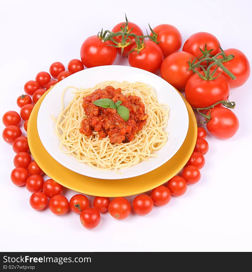 Spaghetti Bolognese on a plate decorated with fresh basil, some tomatoes and cherry tomatoes