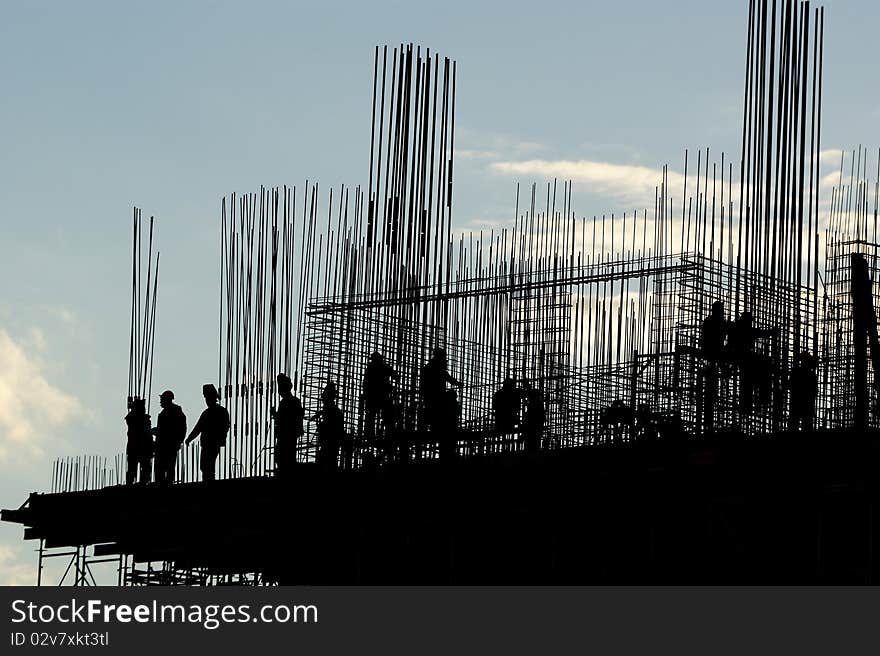 Silhouettes of builders and building structures on the background of a sunset. Silhouettes of builders and building structures on the background of a sunset