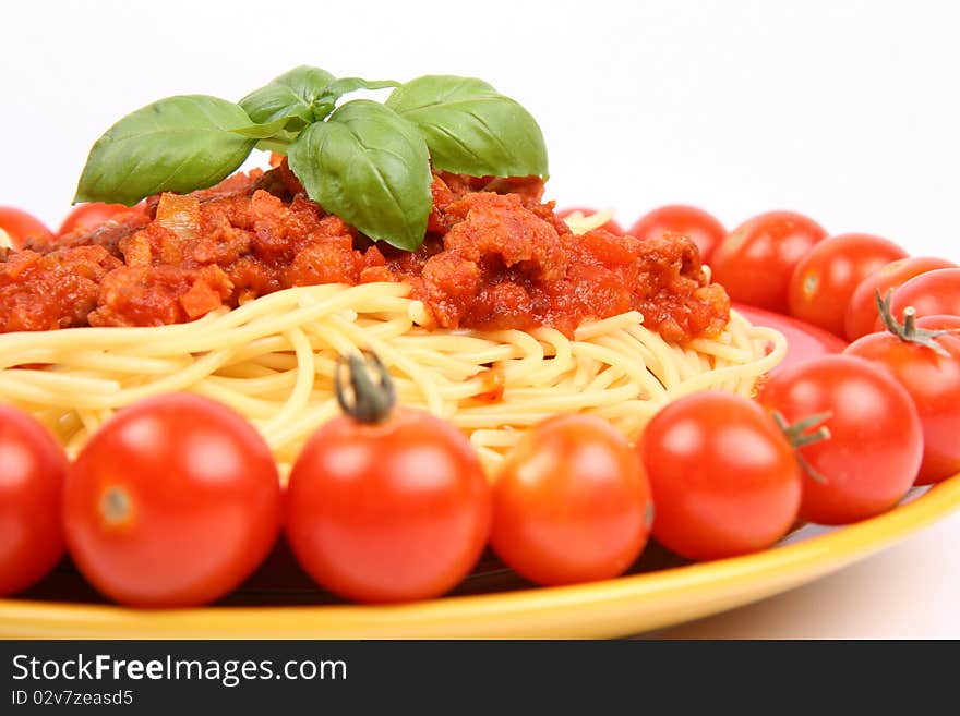 Spaghetti Bolognese on a plate decorated with fresh basil and cherry tomatoes around it