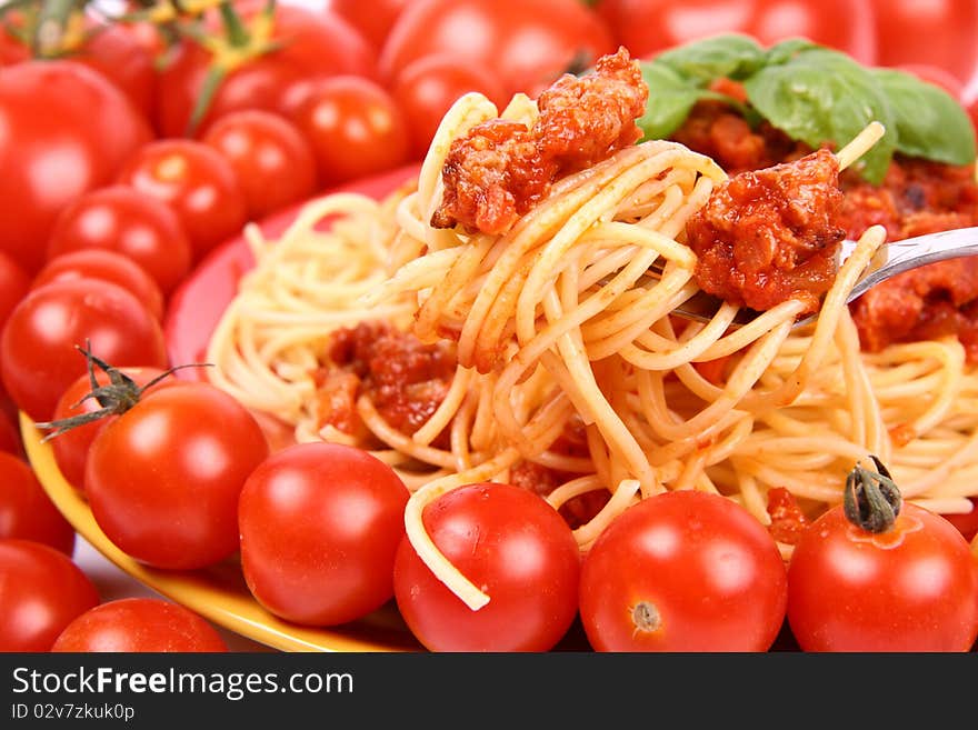 Spaghetti Bolognese on a plate decorated with fresh basil and surrounded with tomatoes and cherry tomatoes in close up