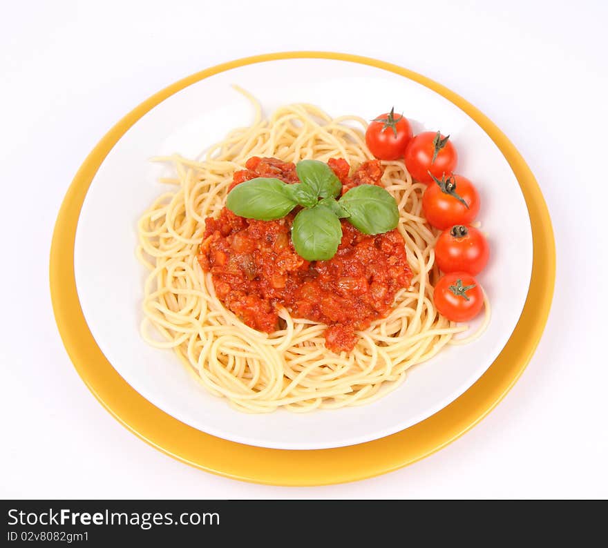 Spaghetti Bolognese on a plate decorated with fresh basil and cherry tomatoes on white background