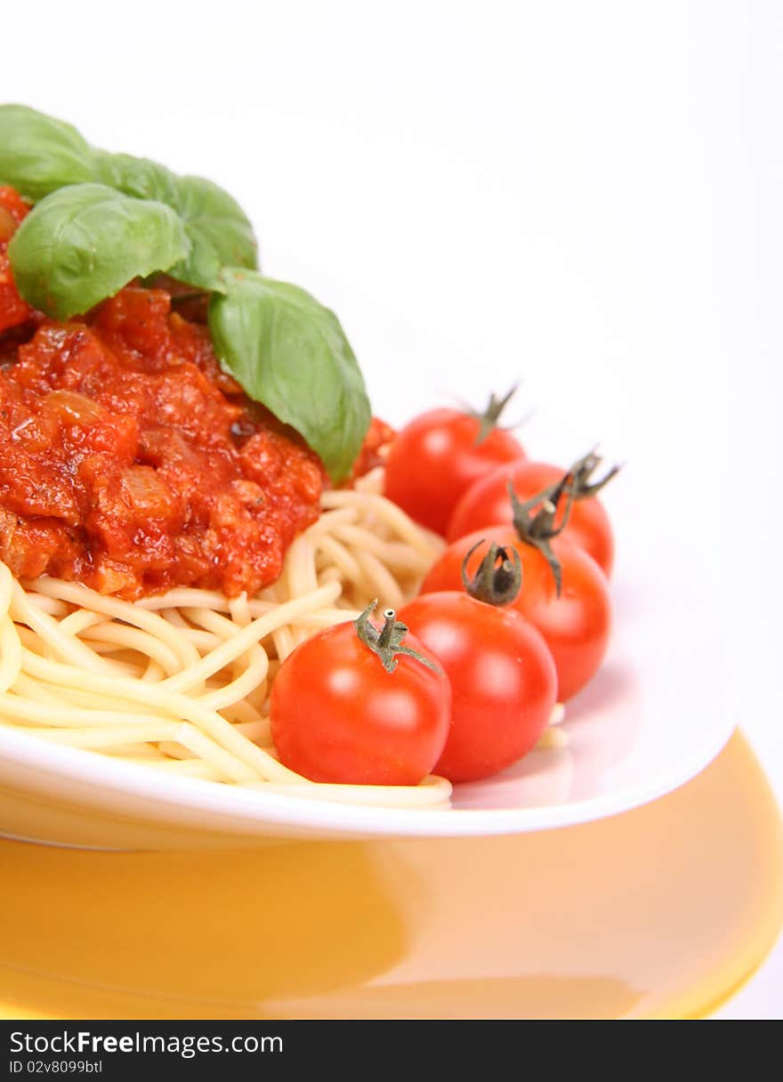 Spaghetti Bolognese on a plate decorated with fresh basil and cherry tomatoes in close up