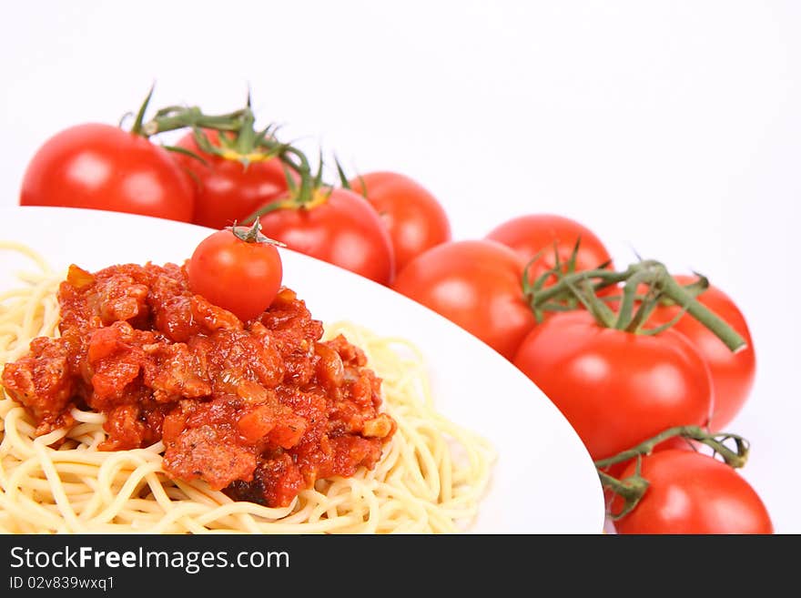 Spaghetti Bolognese on a plate surrounded with tomatoes and decorated cherry tomato