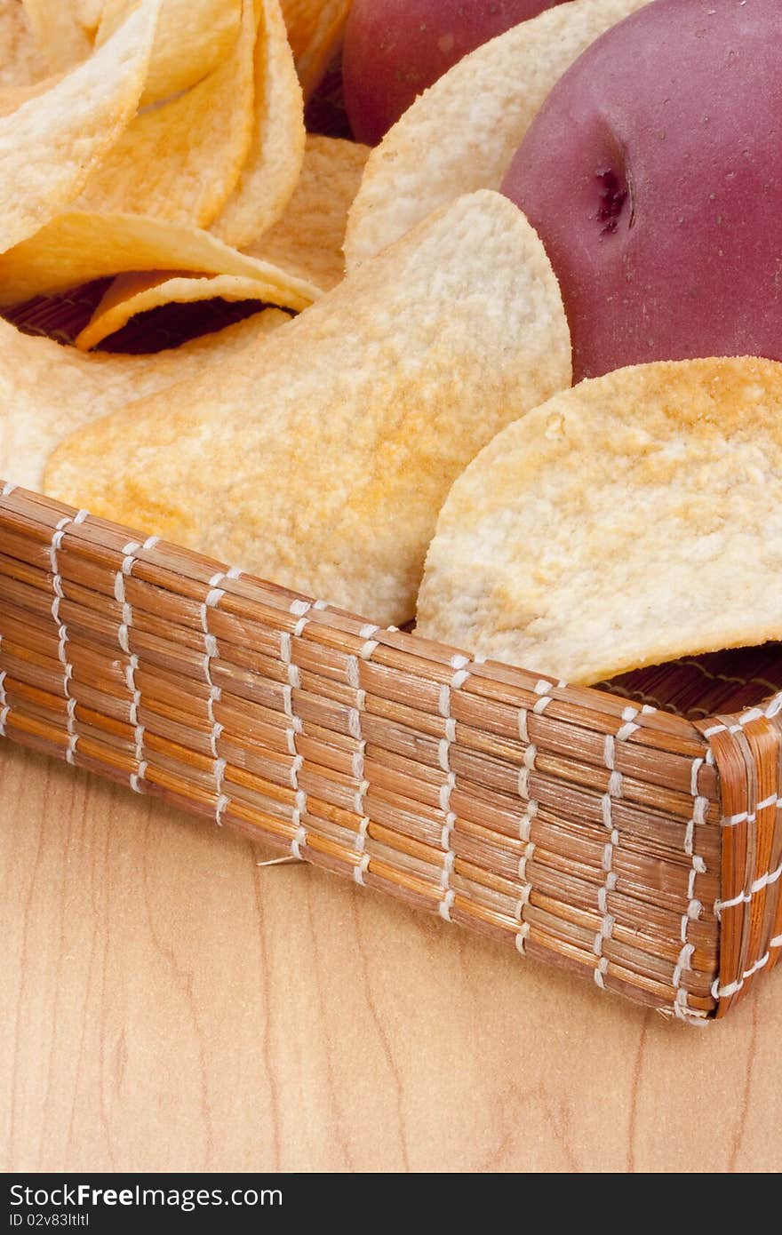 Potato chips with a potato on a wooden tray.