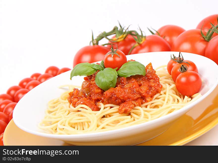 Spaghetti Bolognese on a plate decorated with fresh basil and cherry tomatoes surrounded with regular tomatoes